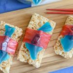 Rice crispy treats topped with gummy sharks and red candy strips.
