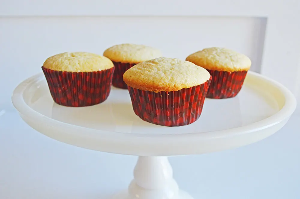 vanilla cupcakes unfrosted on a cake plate