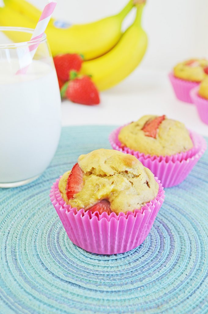 strawberry banana muffins on a blue placemat with milk and fruit