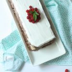 A rectangular chocolate icebox cake with whipped topping and raspberries on top.