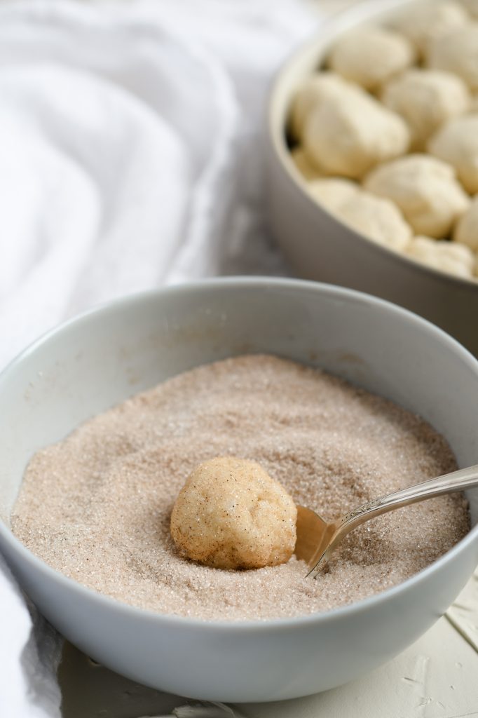Rolling balls of biscuits into cinnamon sugar