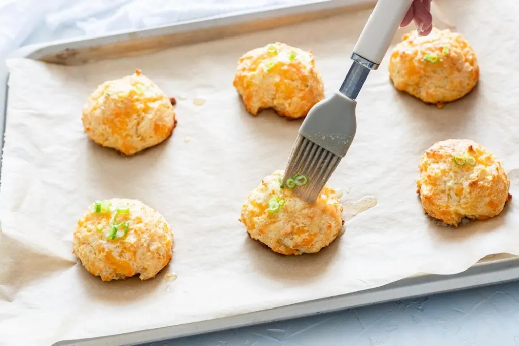 adding garlic butter to the cheddar biscuits