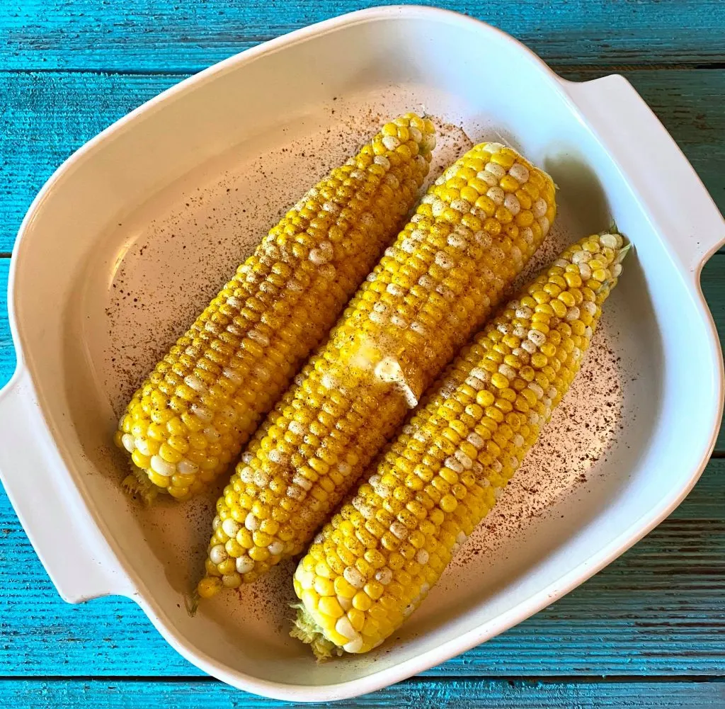 Corn on the Cob with butter and old bay seasoning in white casserole dish