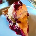 slice of blueberry pie with vanilla ice cream and compote on top