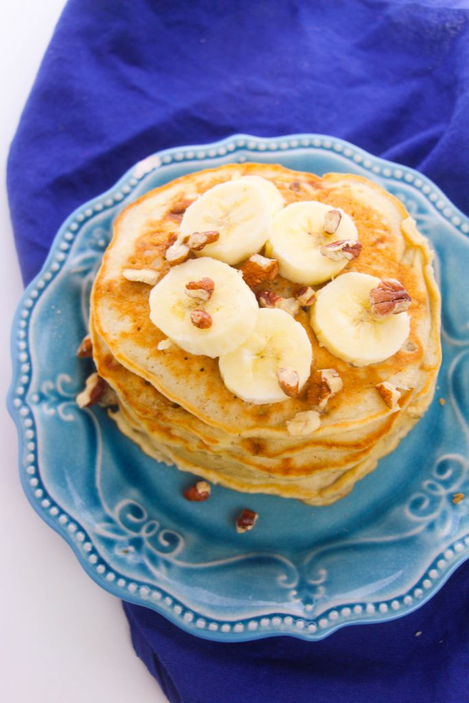 banana pancakes on a blue plate with pecans and banana slices
