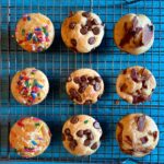 Nine pancake muffins with various toppings on a wire rack.