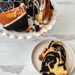 Bundt cake on a stand with a slice cut out, and a plate in front with a marbled slice.