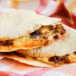 Two folded tortillas filled with seasoned ground beef and melted cheese on a colorful, checkered cloth—perfect for trying out new Mexican food recipes.