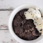 Chocolate lava cake served with two scoops of chocolate chip ice cream in a white bowl.