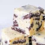 Close-up of creamy white chocolate fudge pieces with chunks of chocolate sandwich cookies, stacked on top of each other—a perfect choice for No Bake Christmas Treats against a light background.