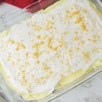 A glass dish of banana pudding topped with whipped cream and cookie crumbs.