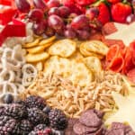 close up of Patriotic-themed charcuterie board with fruit, cheese, pretzels, and crackers arranged in red, white, and blue sections with star-shaped cheese.
