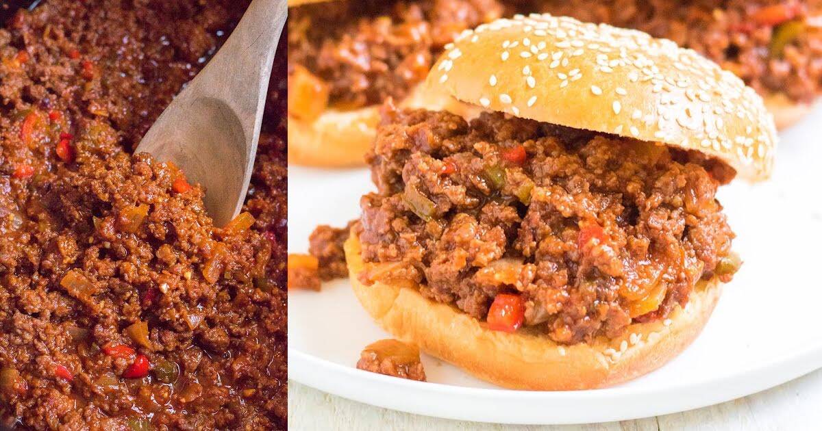 Close-up of sloppy joe meat filling with diced red and green peppers being stirred in a pan, next to a sesame seed bun sandwich filled with the same mixture on a white plate.