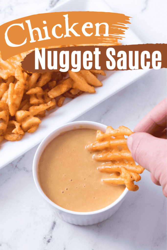A hand dips a waffle fry into a small bowl of Chicken Nugget Sauce. In the background, more waffle fries sit on a plate. The image features text that reads “Chicken Nugget Sauce.”.