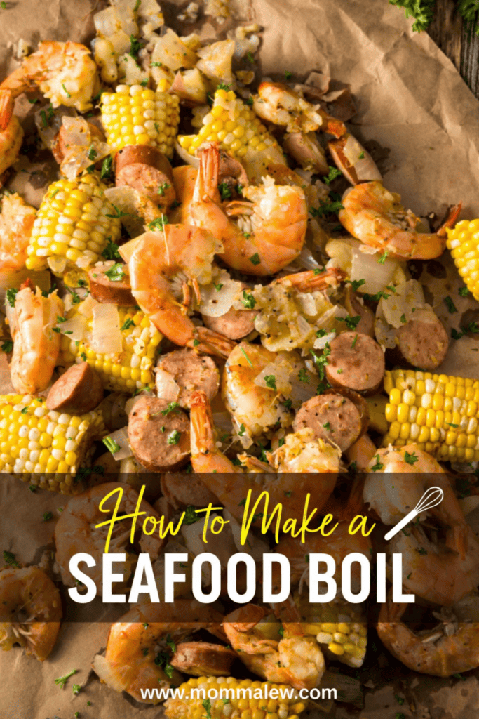 A close-up of a Seafood Boil with shrimp, sausage, corn on the cob, and potatoes on parchment paper, garnished with herbs. Text on image: How to Make a Seafood Boil www.mommalew.com.
