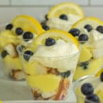Lemon blueberry parfait in a clear cup with whipped cream and a lemon slice on top.
