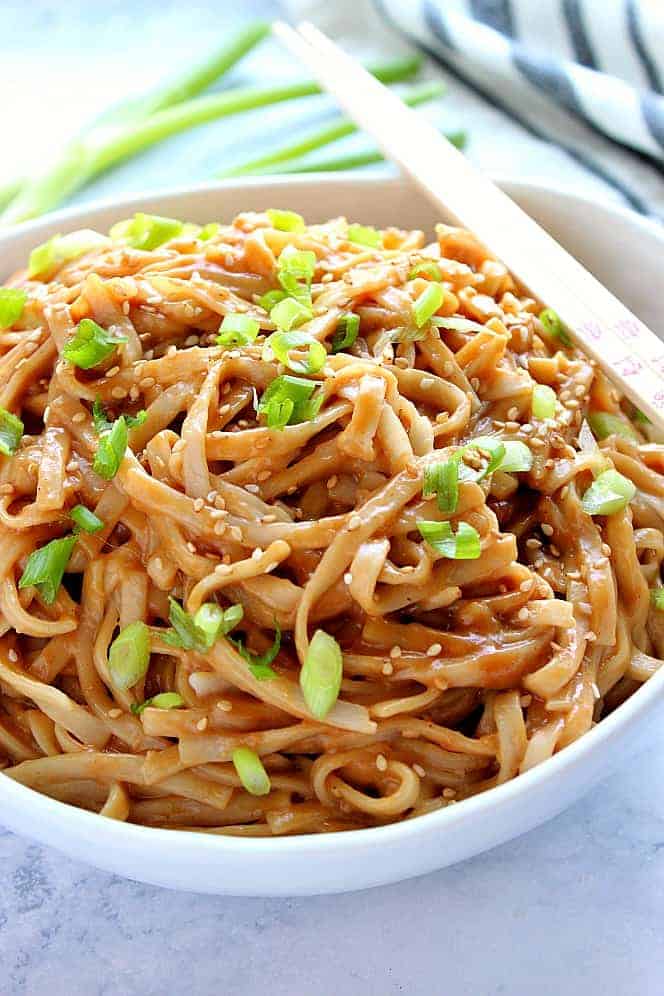 A bowl of noodles topped with chopped green onions and sesame seeds, with a pair of chopsticks resting on the bowl—perfect as one of your flavorful Thai side dishes.