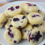 A plate of mini blueberry pancake muffins stacked on a white plate.