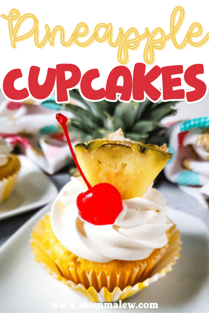 A pineapple cupcake topped with white frosting, a maraschino cherry, and a pineapple slice sits on a plate. Bold text reads Pineapple Cupcakes above the delicious treat. The website www.mommalew.com appears at the bottom.