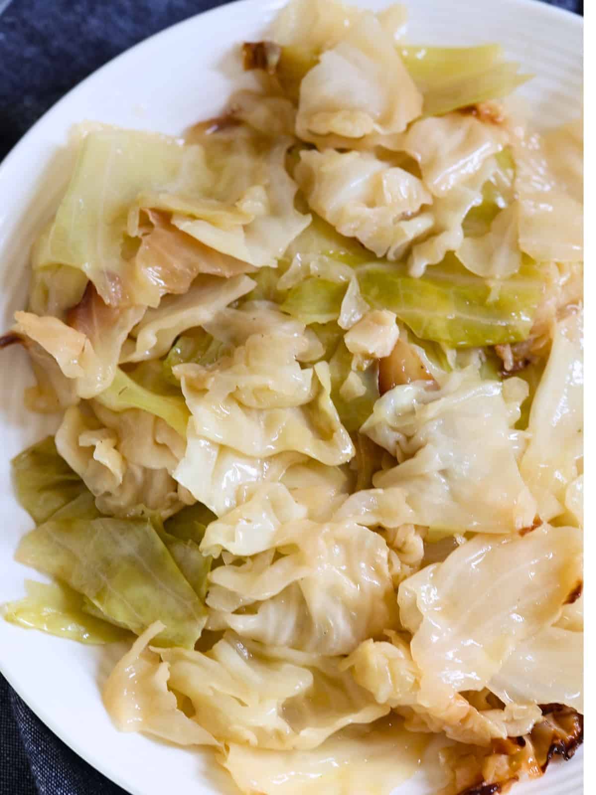 A white plate filled with cooked cabbage leaves, slightly browned at the edges, with a glossy, tender texture—perfect as one of your slow cooker side dishes for BBQ.