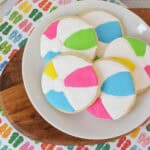A white plate with beach ball sugar cookies decorated in blue, green, pink, yellow, and white.