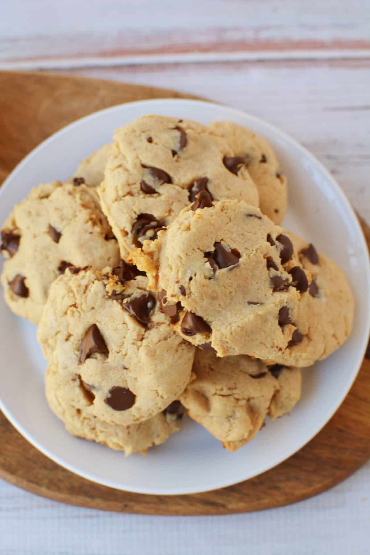 A white plate filled with several thick, soft Bisquick Peanut Butter Chocolate Chip Cookies sits on a wooden board against a light background.