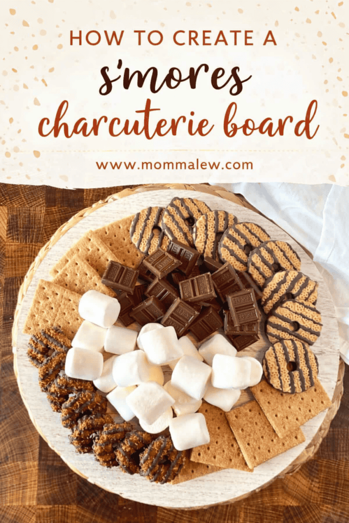 A s’mores charcuterie board featuring graham crackers, chocolate bars, marshmallows, and cookies arranged in a circle on a round wooden board, with text above that reads How to Create a S’mores Charcuterie Board.