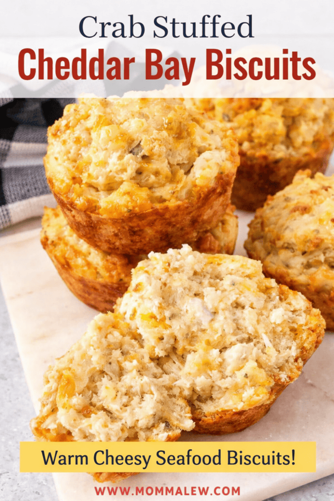 Golden, cheesy crab stuffed cheddar bay biscuits are stacked on a marble board. One biscuit is cut open, revealing a moist, flavorful interior. Text overlay reads, Crab Stuffed Cheddar Bay Biscuits—Warm Cheesy Seafood Biscuits!.