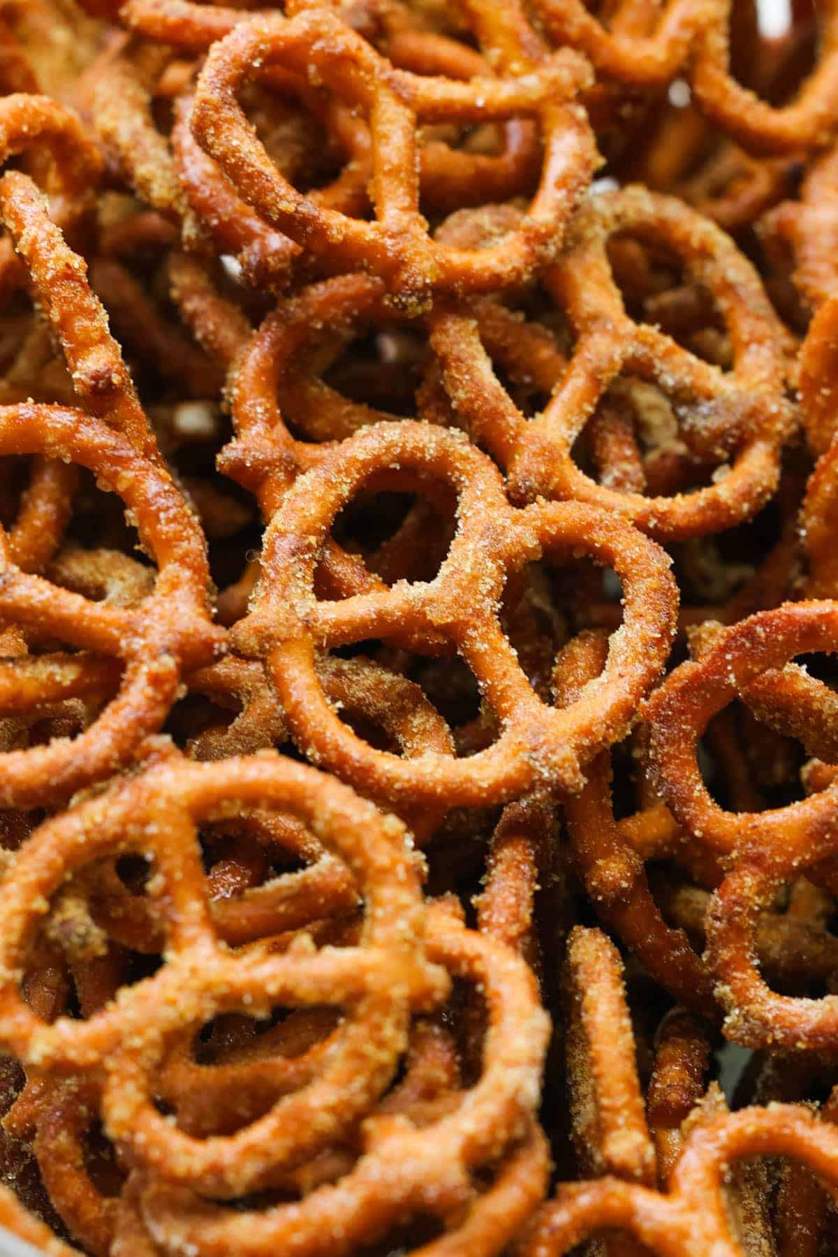 A close-up view of a pile of crunchy pretzels coated with a layer of seasoning, highlighting their golden-brown color and textured surface.