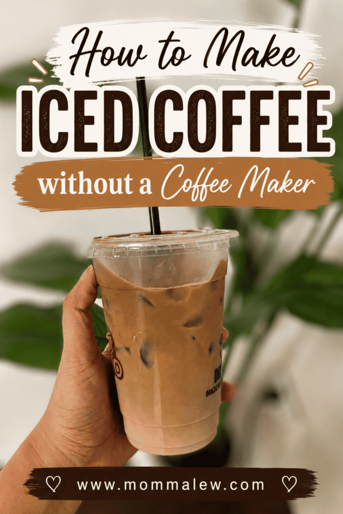 A hand holds a plastic cup of Iced Coffee without Coffee Maker, complete with a black straw, in front of vibrant green leaves. Text on the image reads: How to Make Iced Coffee without a Coffee Maker and www.mommalew.com.