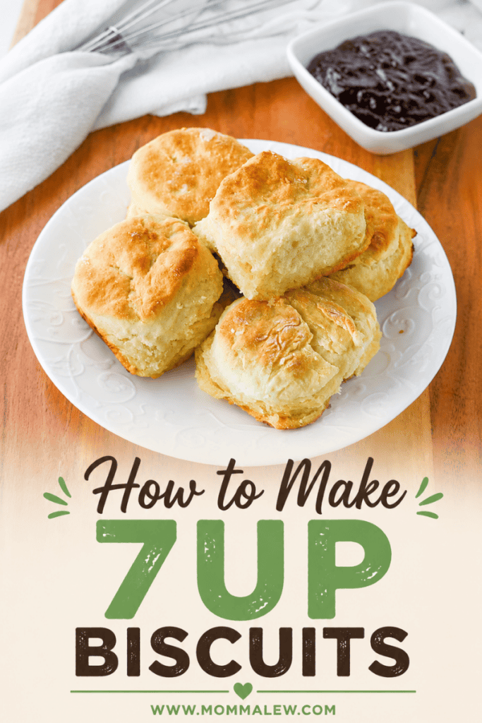A plate of golden, flaky 7Up Biscuits sits on a white dish, next to a small bowl of jam. Text on the image reads: How to Make 7UP Biscuits with the website www.mommalew.com below.