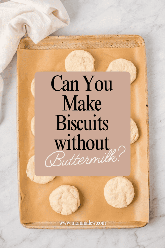 A baking sheet lined with parchment paper holds nine unbaked biscuits. Text overlay reads: Can you make biscuits without buttermilk? www.mommalew.com. A white cloth is in the top left corner.