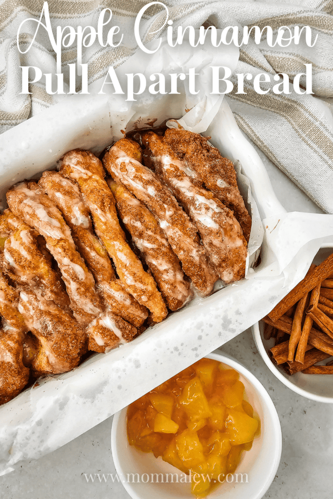 Apple Cinnamon Pull Apart Bread topped with glaze sits in a parchment-lined pan, accompanied by a bowl of apple filling and cinnamon sticks. Text on the image reads Apple Cinnamon Pull Apart Bread.