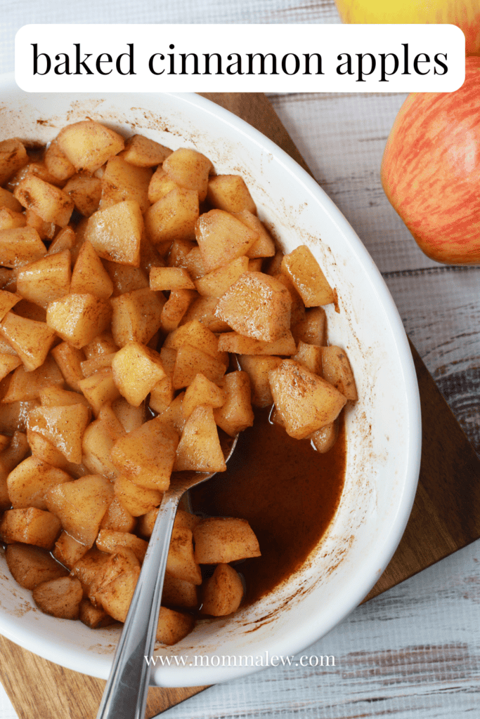 A white dish filled with Baked Cinnamon Apples sits on a wooden board. A spoon rests in the dish, and an apple is in the background. Text reads Baked Cinnamon Apples.