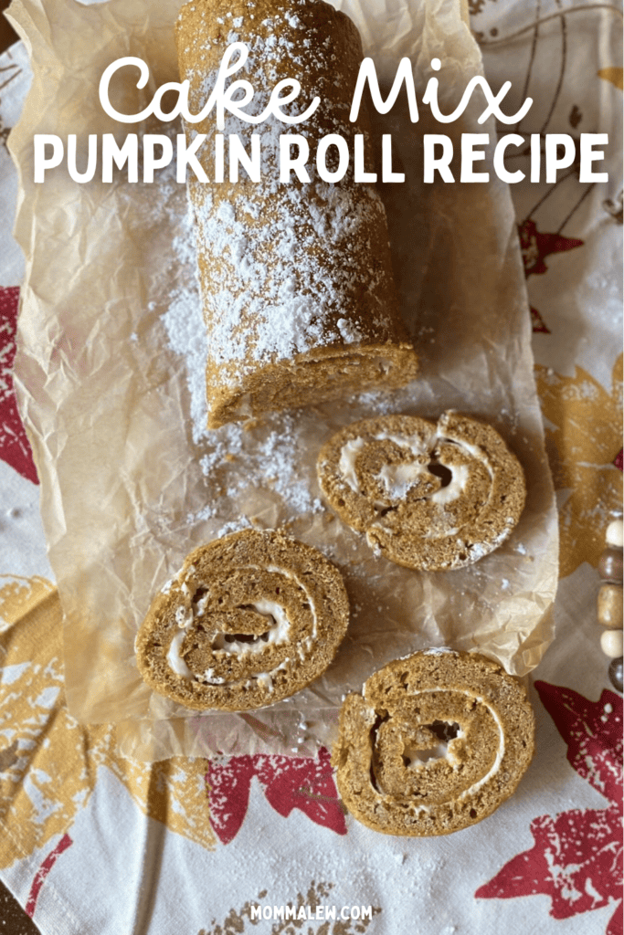A pumpkin roll with cream cheese filling, partially sliced, sits on parchment paper atop a fall-themed tablecloth. Text reads: Pumpkin roll recipe with cake mix and mommalew.com.