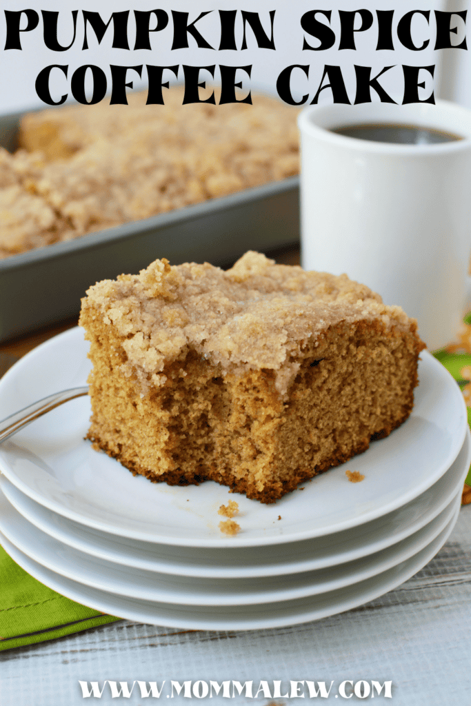 A piece of Krusteaz Pumpkin Coffee Cake on stacked white plates, next to a fork and a cup of coffee. Text reads Pumpkin Spice Coffee Cake and www.mommalew.com.