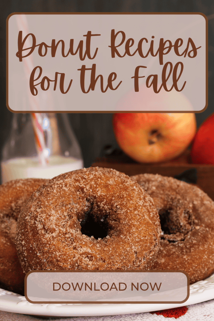 Three sugar-coated donuts are stacked on a plate with apples and a bottle of milk in the background. Text reads: Donut Recipes for the Fall, featuring creative Fall Donut Decorating Ideas—Download Now.